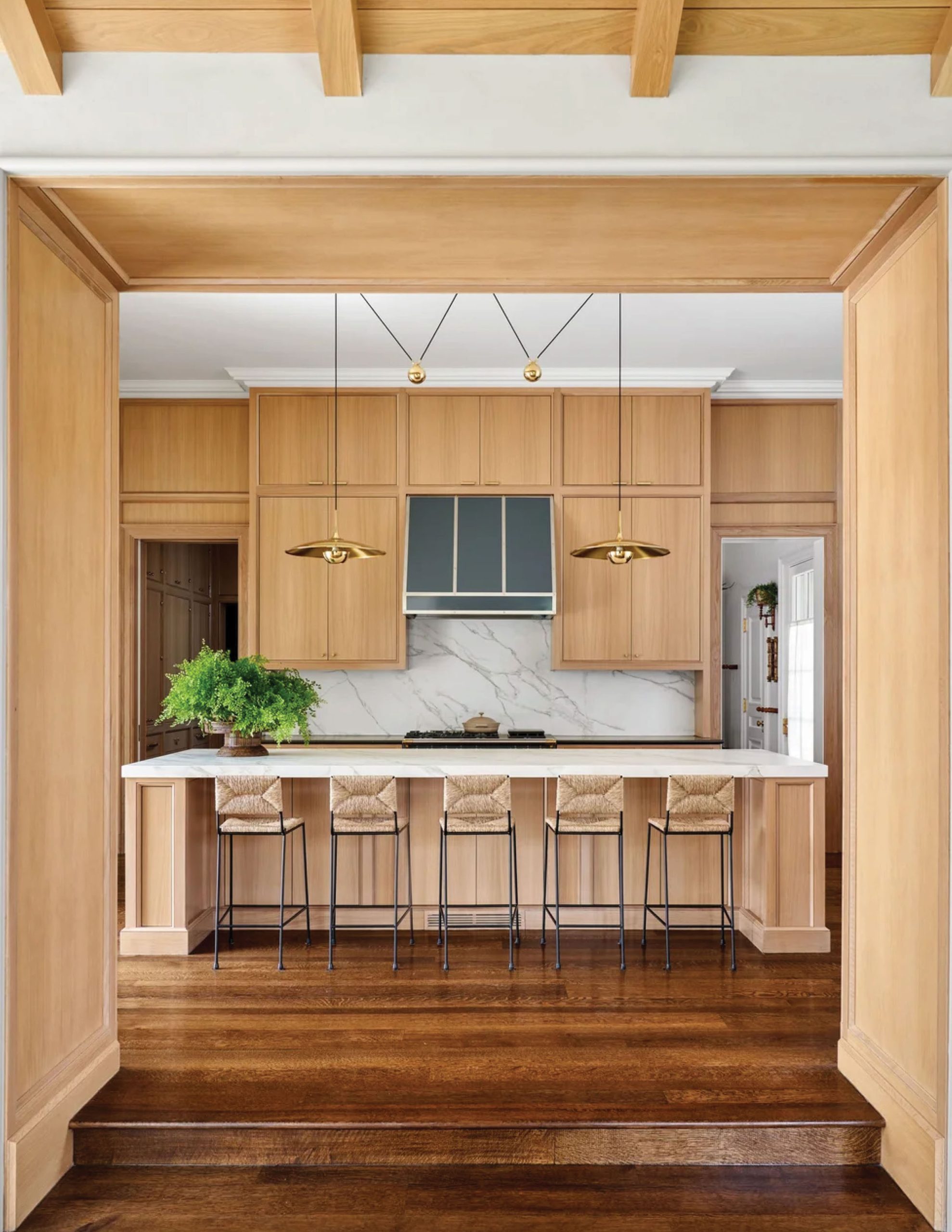 Park Cities – Crescent — Kitchen viewed through white oak portal with marble backsplash and brass pendant lights