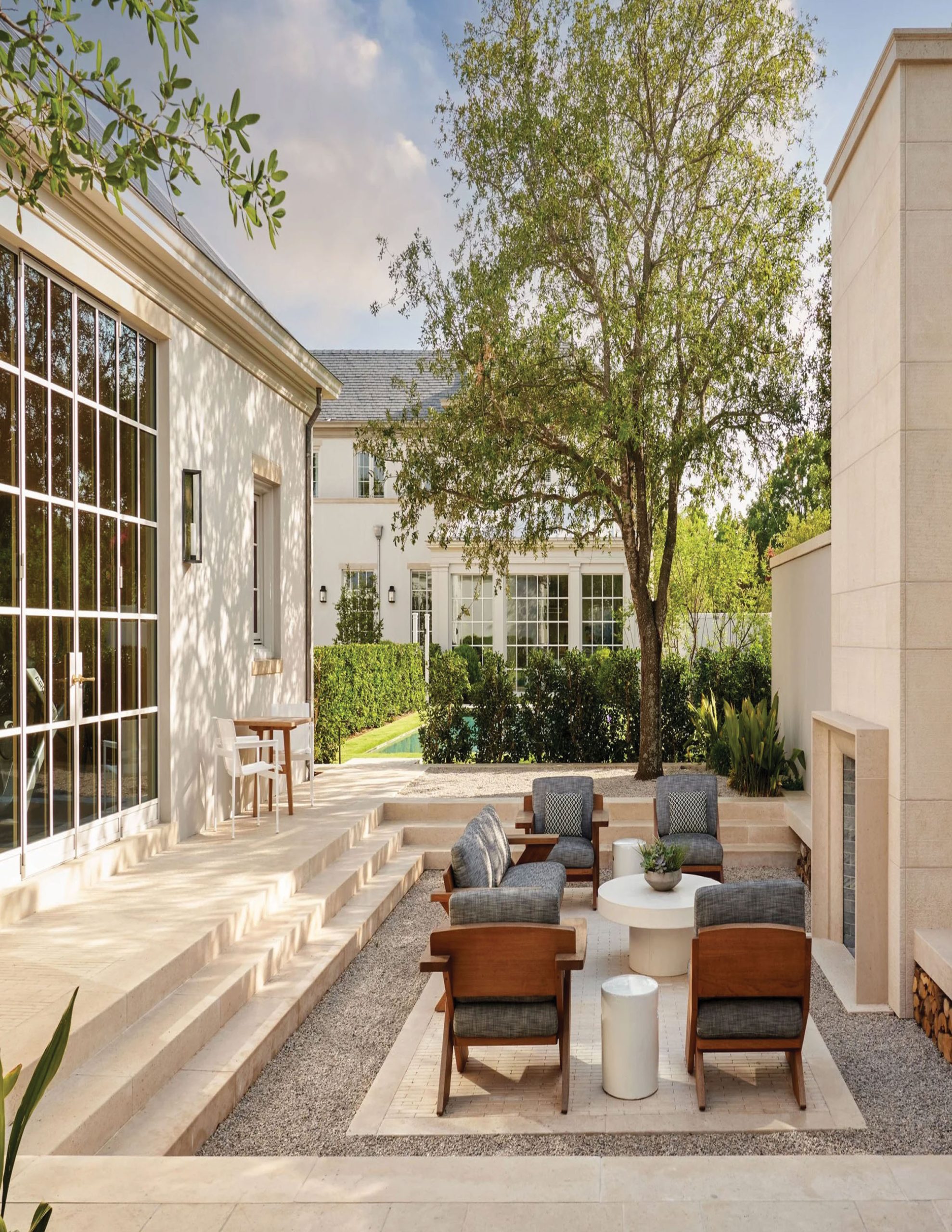Park Cities – Crescent — Courtyard seating area with stone fireplace, gravel, and house wings beyond