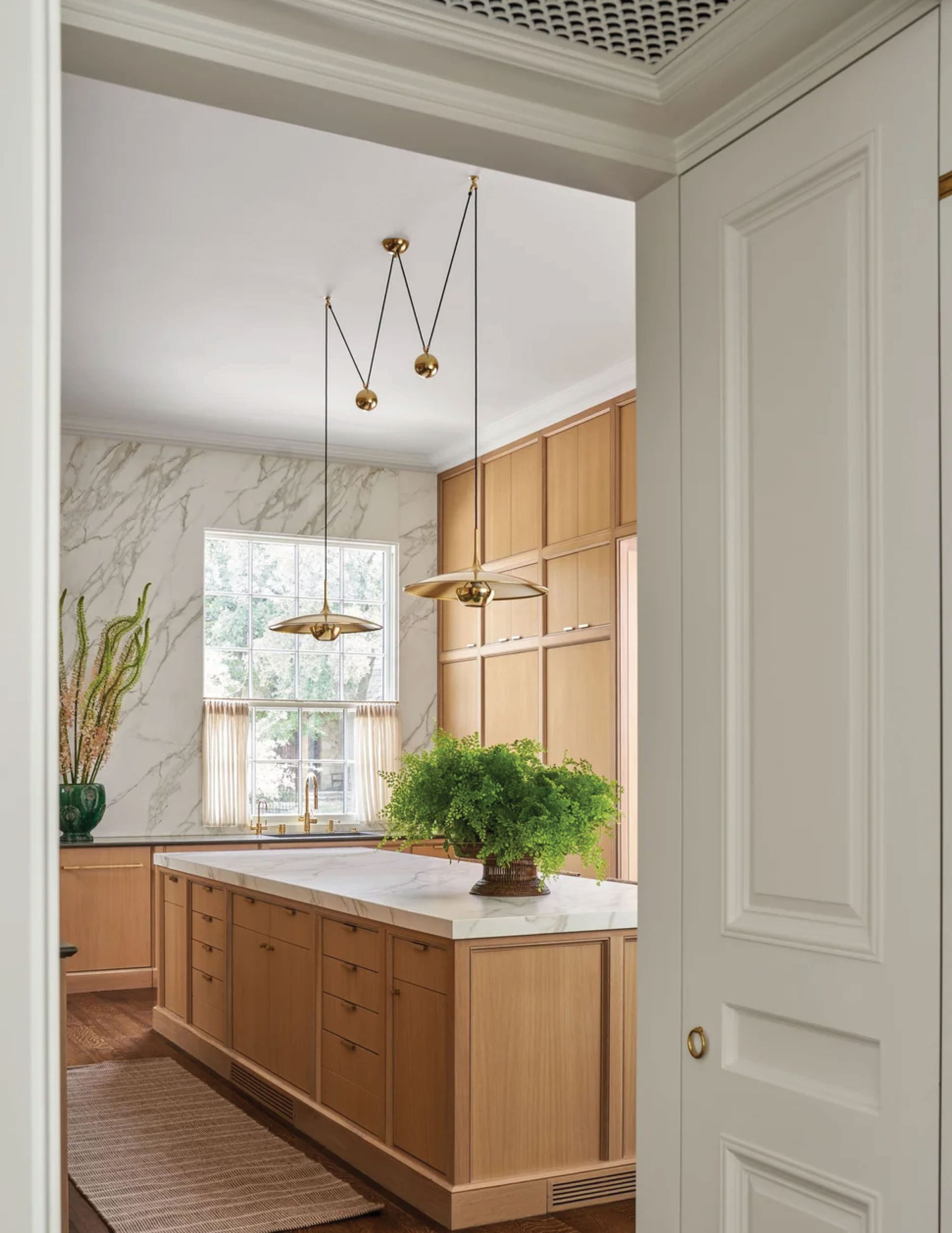 Park Cities – Crescent — Primary kitchen with white oak cabinetry, marble island, and sculptural brass pendants