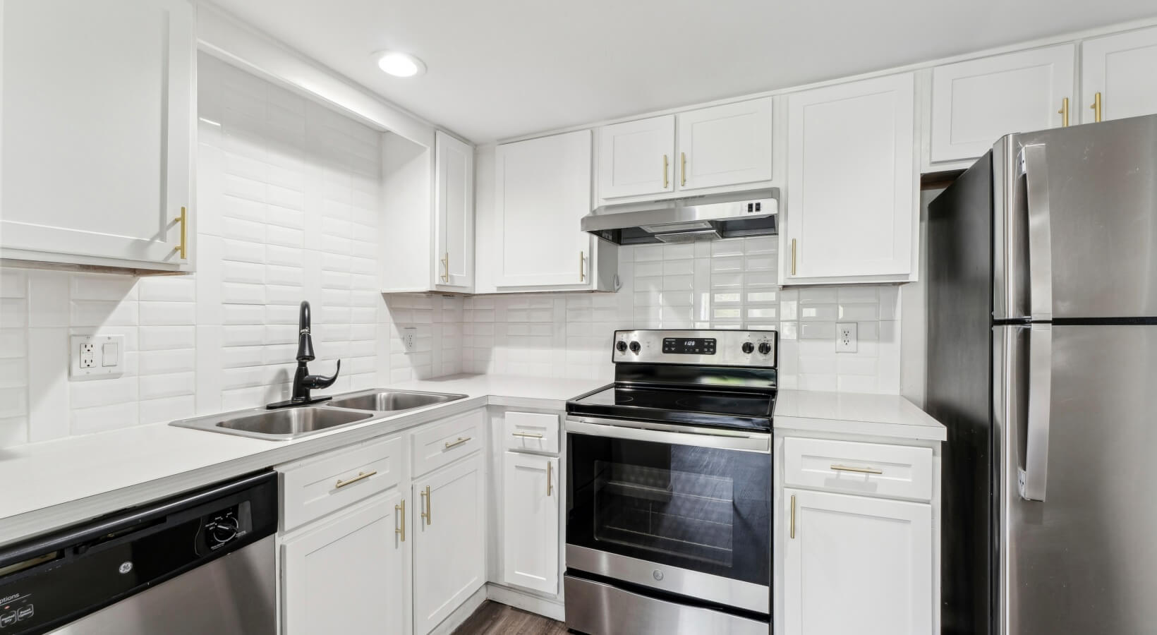 The Lennox — Renovated kitchen with white cabinets, gold hardware, and subway tile backsplash