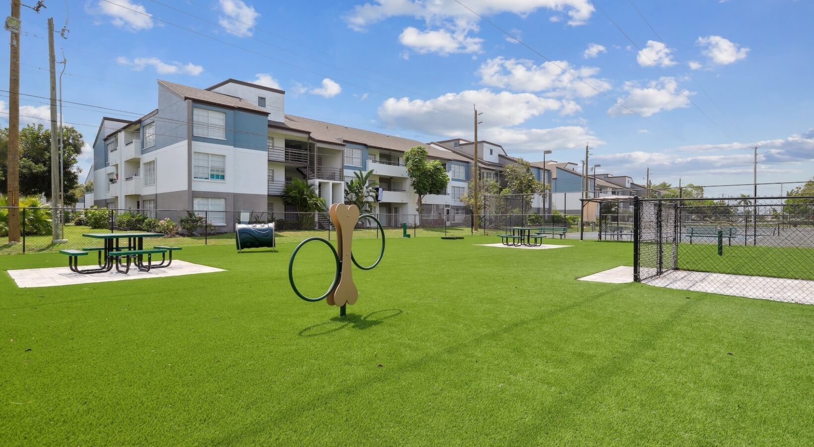 The Lennox — New dog park with artificial turf and agility equipment beside the community buildings